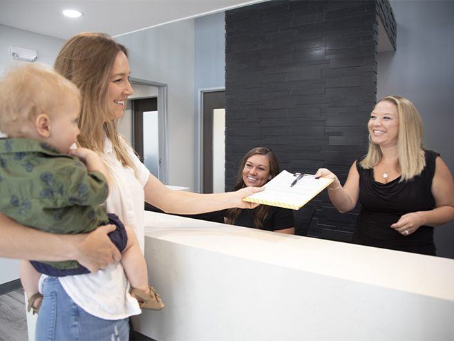 Mother and child checking in at dental office reception desk