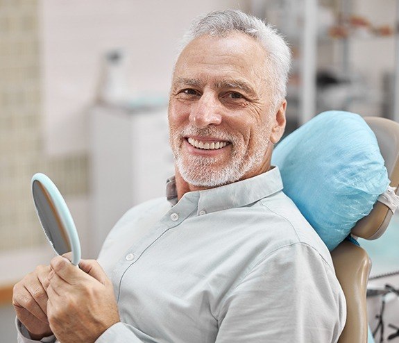 Man looking at smile after dental implant supported denture placement