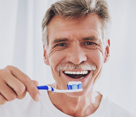 Man brushing his teeth after all on four dental implant restoration