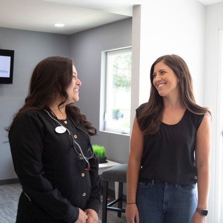 Dental team member laughing with patient in Longmont dental office