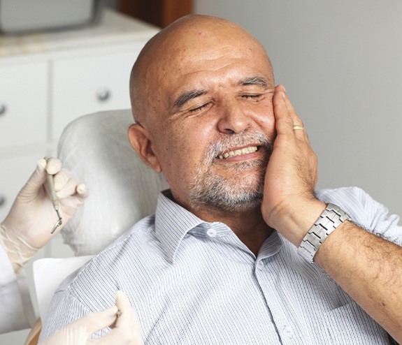 Man with partial dislodge tooth holding cheek in pain