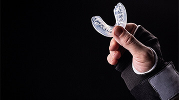 Person holding a custom mouthguard from emergency dentist in Longmont