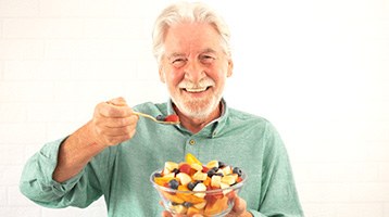 Man eating a bowl of fruit with dentures