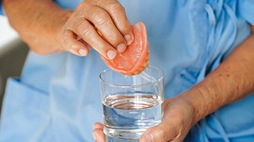 Person placing dentures in a glass of water