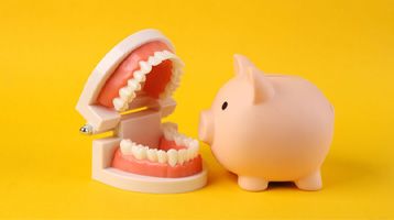 dentures sitting next to a piggy bank against a yellow background 