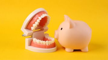 dentures sitting next to a piggy bank against a yellow background