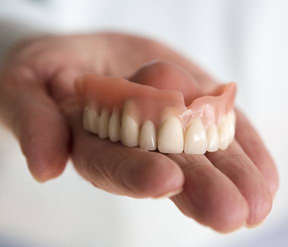 Hand holding a dneture during maintenance treatment