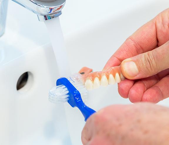 Patient brushing their removable denture