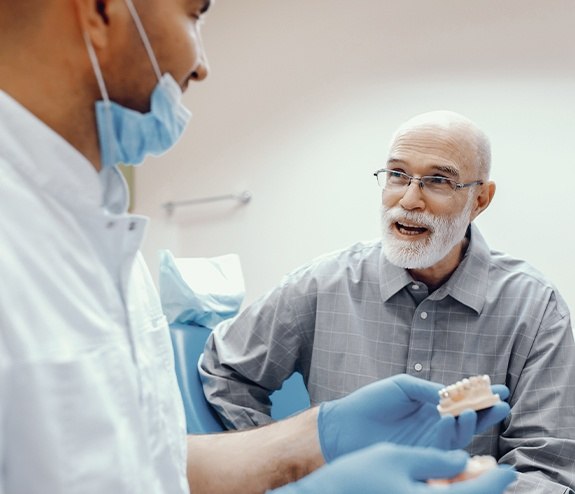 Dentist and patient looking at removable dental implant retained denture