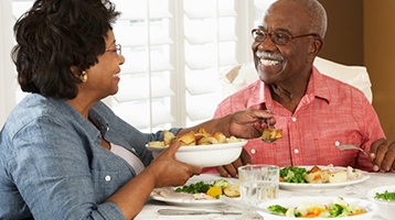 a mature couple smiling and enjoying a healthy meal