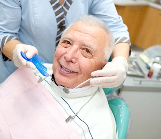 Older man with dental implants in Longmont smiling during exam