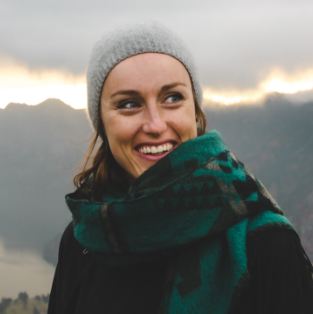 Woman wearing beanie and scarf with mountains in background