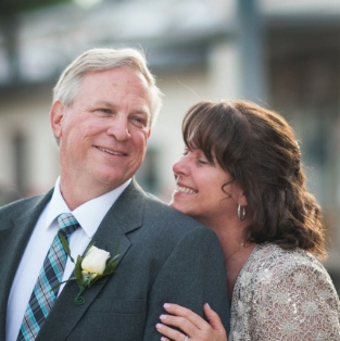 Smiling man and woman holding each other at outdoor wedding