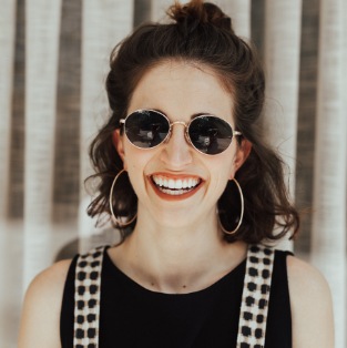 Woman wearing sunglasses and grinning outdoors