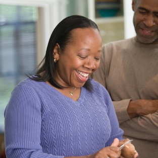 Woman smiling while peeling a potato in kitchen