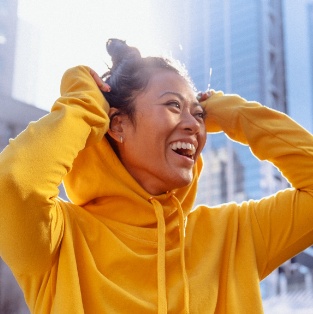 Grinning woman wearing yellow hoodie on a city street