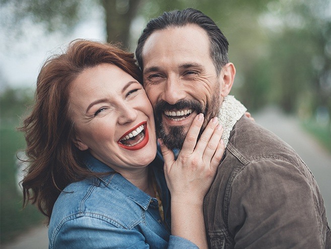 Man and woman smiling after dental implant tooth replacement