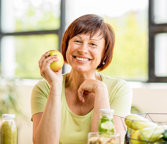 Woman eating an apple after dental implant tooth replacement