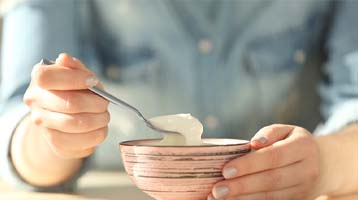 woman eating bowl of yogurt after dental implant surgery in Longmont