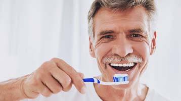 man brushing teeth after getting dental implants in Longmont