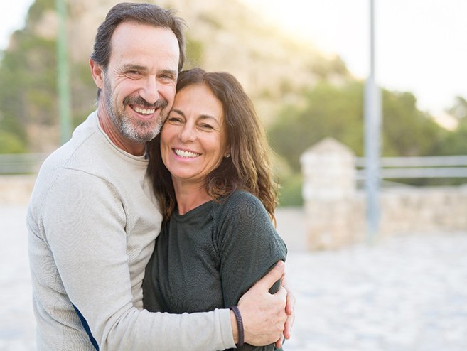 An older couple with dental implants in Longmont smiling outside