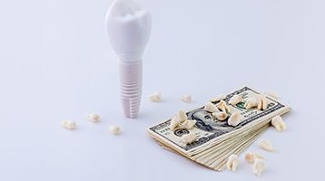 Dental implant in Longmont next to money and model teeth