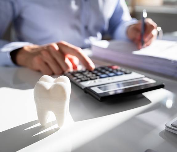 Dental team member using calculator while determining dental insurance coverage