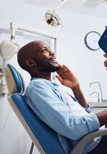 Man in blue collared shirt sitting in dental chair before exam