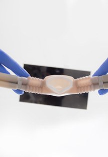 Bird’s eye view of hands in blue gloves holding nitrous oxide nose mask over white background