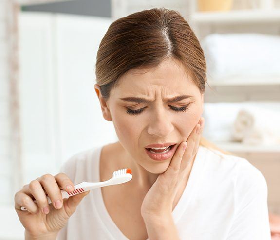 Woman in pain from gum disease holding cheek