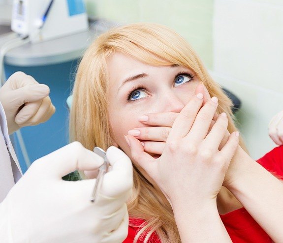 Woman in need of sedation dentistry covering her mouth