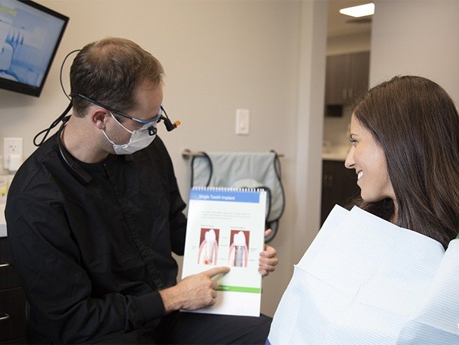 Doctor showing patient information about dental implant tooth replacement