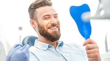 man smiling in dental mirror