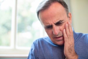 Man in blue shirt with tooth pain who needs dentist