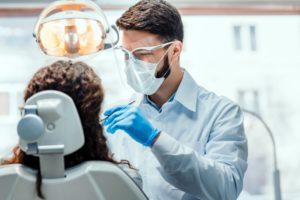 a patient visiting their dentist in Longmont, who is wearing a mask and face shield