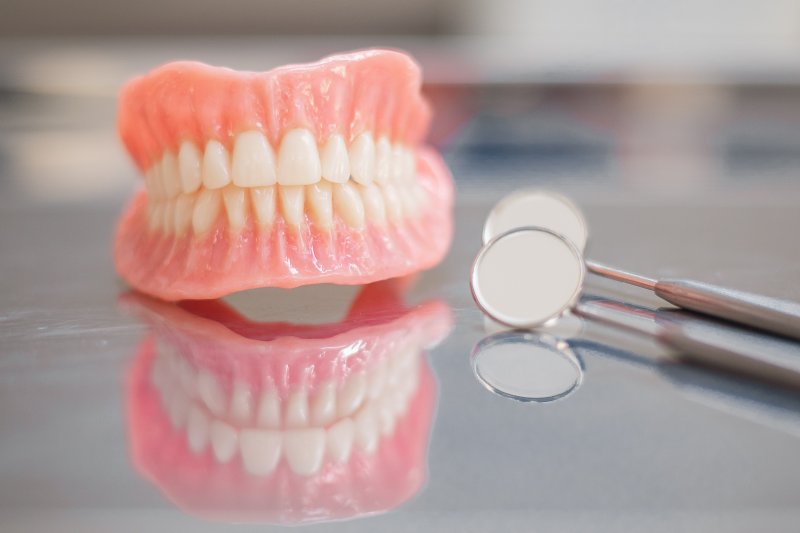 Full dentures next to a dental mirror