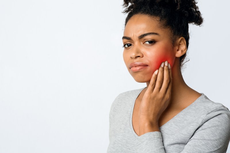 woman holding her cheek due to a toothache in Longmont