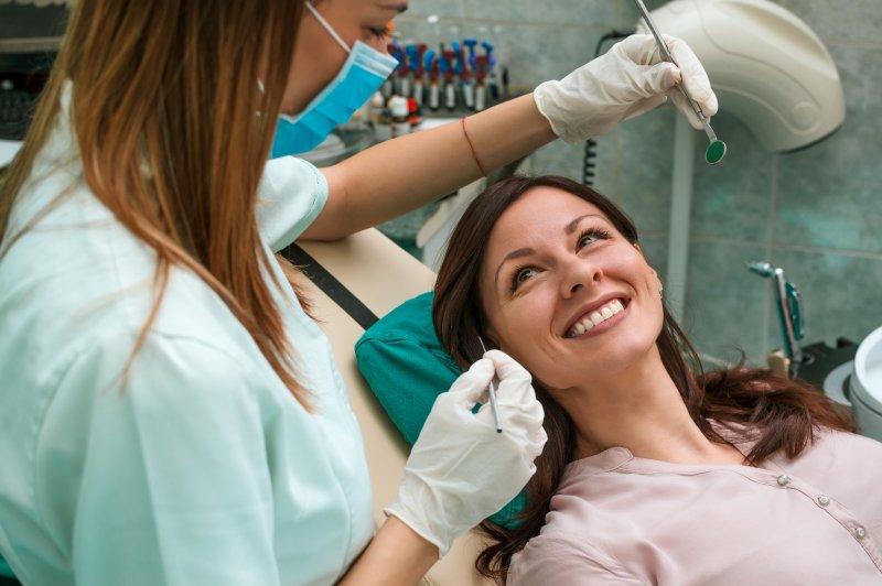 A smiling woman looking up at her dentist