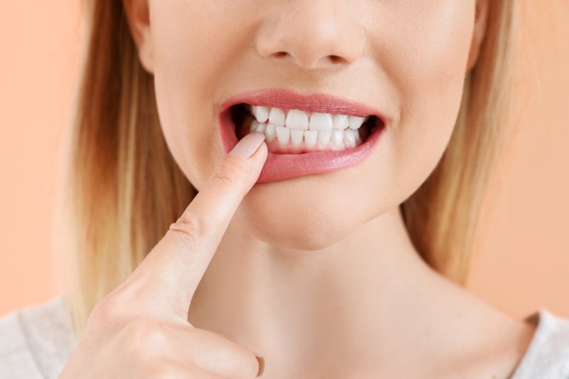 A beautiful woman pointing to one of her teeth