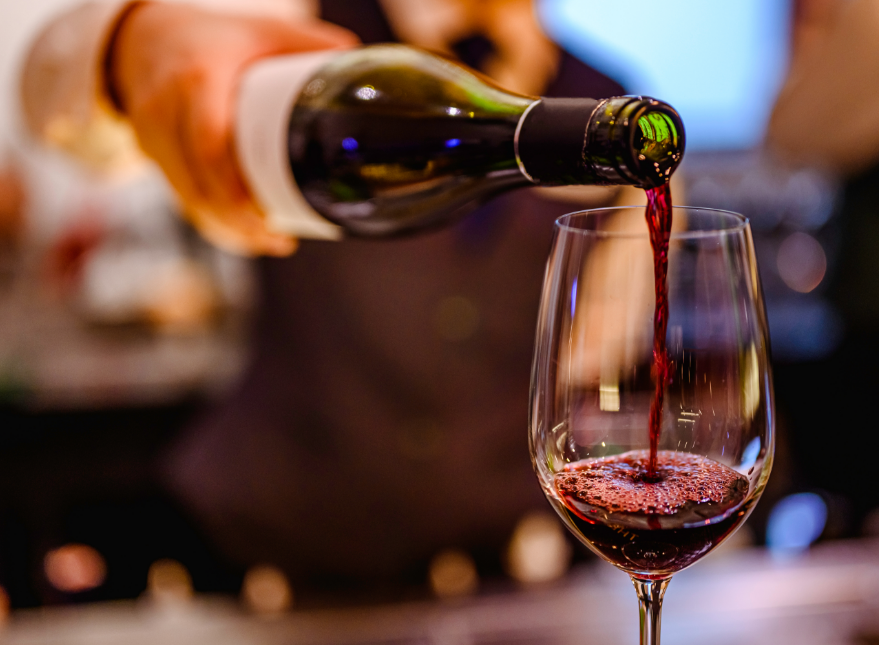 Server pouring glass of red wine
